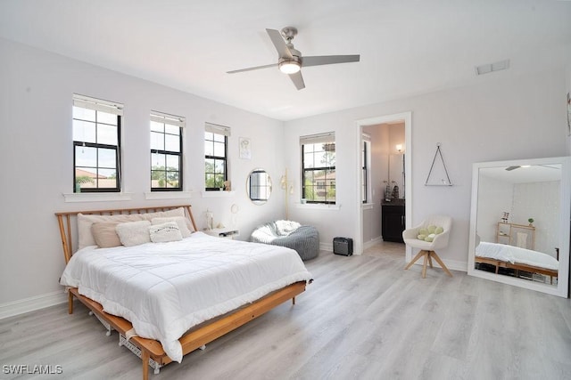 bedroom with ceiling fan, ensuite bath, light wood-type flooring, and multiple windows