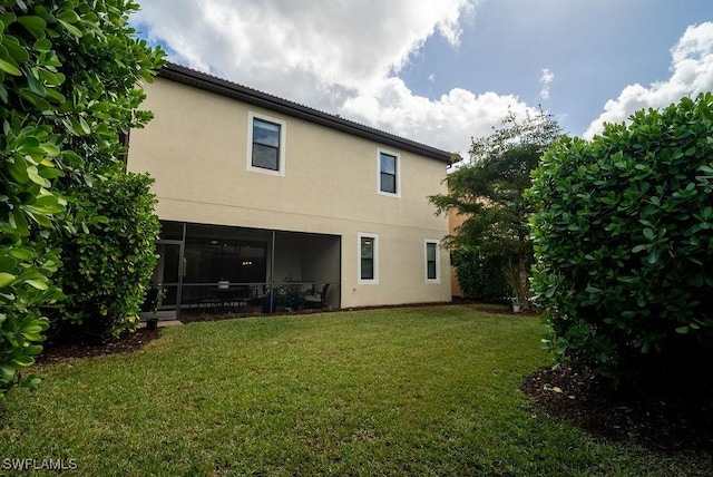 back of property with a lawn and a sunroom