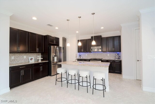 kitchen with appliances with stainless steel finishes, a kitchen breakfast bar, ornamental molding, a kitchen island with sink, and decorative light fixtures