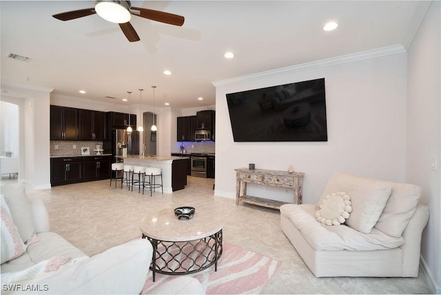 living room with ceiling fan, ornamental molding, and sink