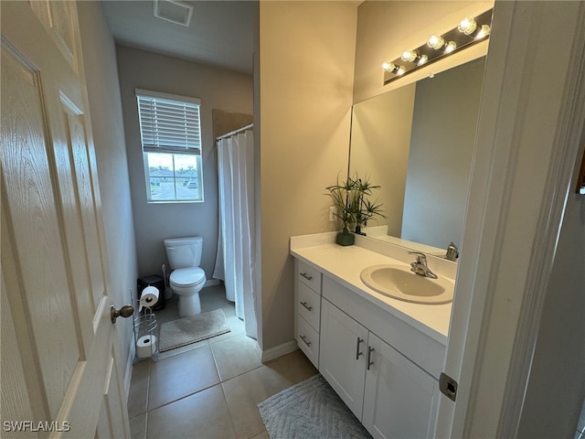 bathroom with toilet, vanity, and tile patterned flooring