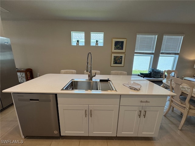 kitchen featuring a center island with sink, appliances with stainless steel finishes, light tile patterned floors, sink, and white cabinets