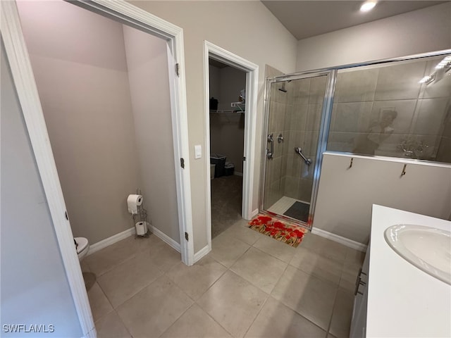 bathroom with a shower with door, vanity, toilet, and tile patterned floors