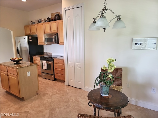 kitchen with dark stone counters, a center island, hanging light fixtures, appliances with stainless steel finishes, and light brown cabinetry