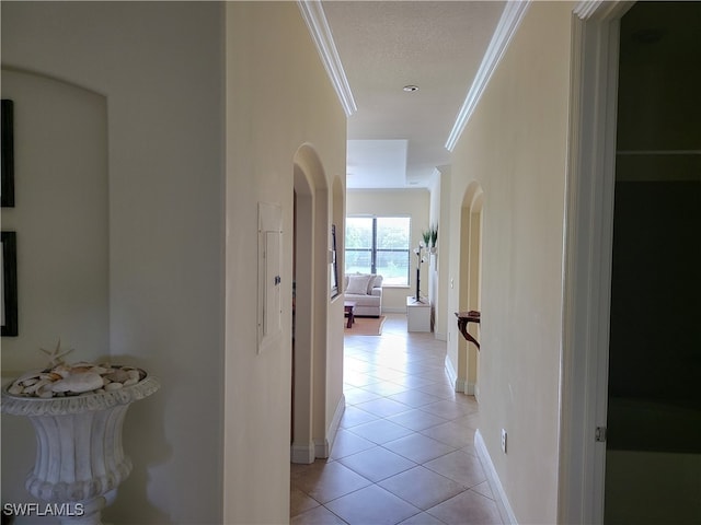 corridor with a textured ceiling, light tile patterned flooring, and crown molding