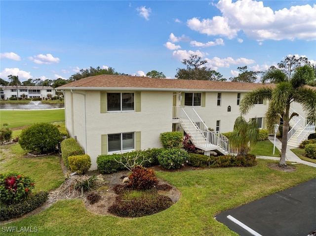 view of front of property with a water view and a front lawn