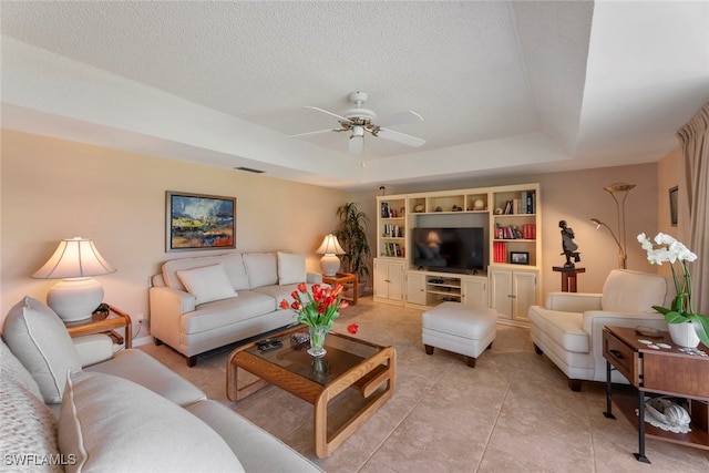 tiled living room with a textured ceiling, ceiling fan, and a raised ceiling