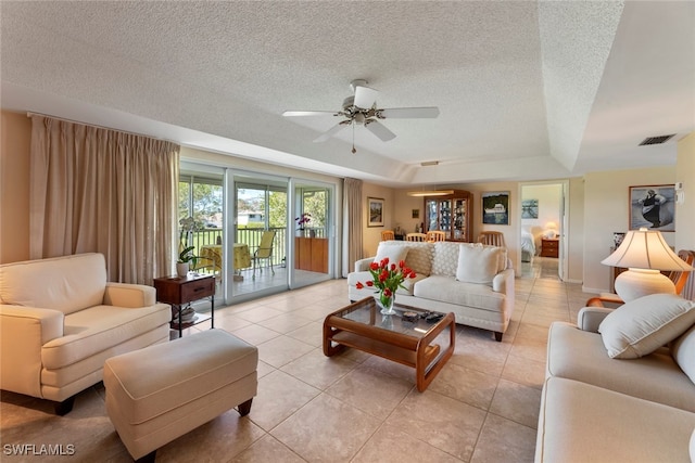 living room featuring a textured ceiling, ceiling fan, a raised ceiling, and light tile patterned floors