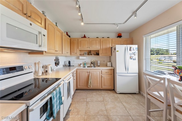 kitchen featuring sink, track lighting, light brown cabinetry, light tile patterned floors, and white appliances