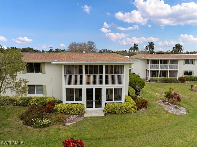 back of house featuring a sunroom, a yard, and a balcony