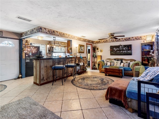 tiled living room with ceiling fan and a textured ceiling