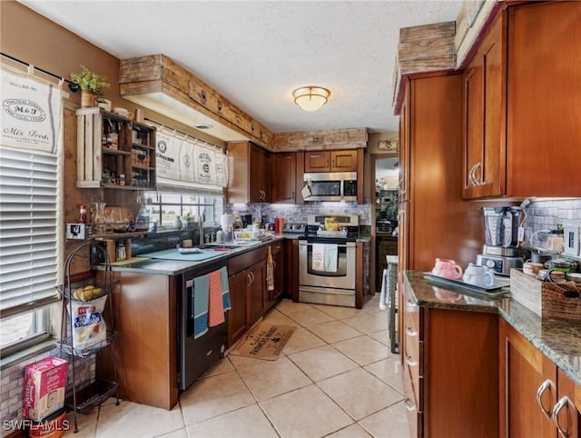 kitchen featuring light tile patterned floors, appliances with stainless steel finishes, dark stone countertops, and tasteful backsplash