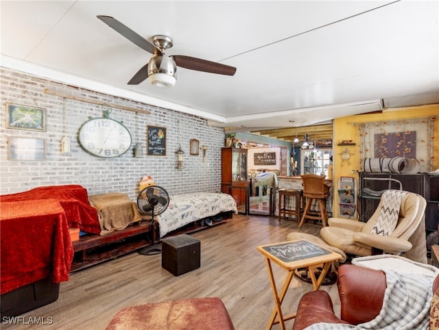 bedroom with ceiling fan, brick wall, and hardwood / wood-style flooring