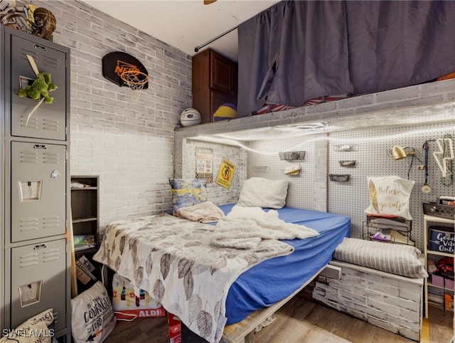 bedroom featuring brick wall and light hardwood / wood-style flooring