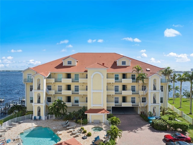 view of building exterior with a community pool and a water view