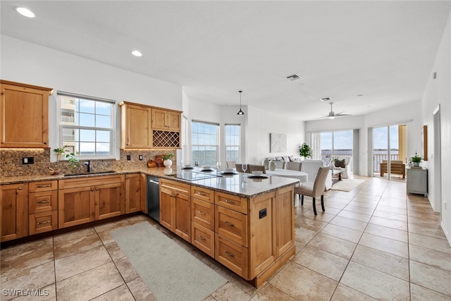 kitchen featuring kitchen peninsula, sink, decorative light fixtures, light stone countertops, and decorative backsplash