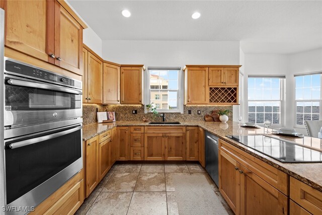 kitchen featuring sink, a healthy amount of sunlight, light stone countertops, and stainless steel appliances