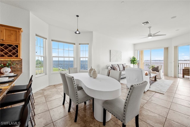 tiled dining area featuring a water view and ceiling fan