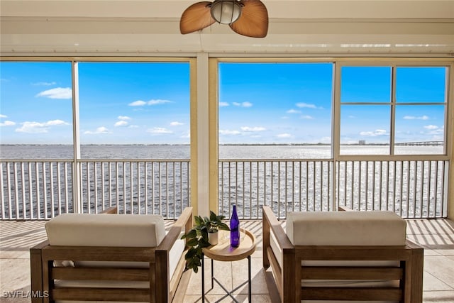 sunroom with ceiling fan and a water view