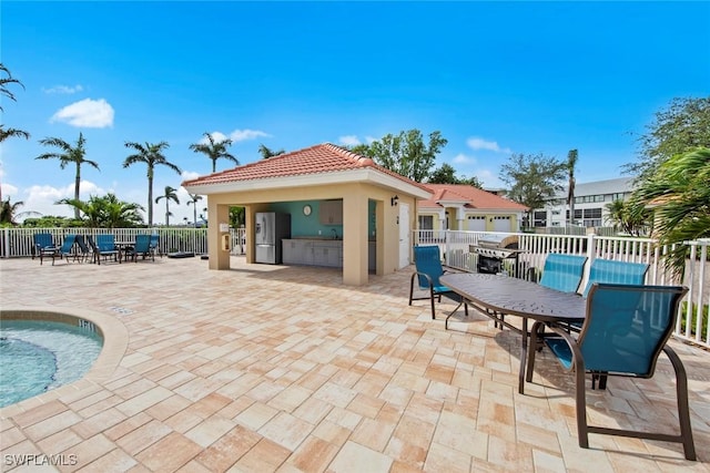 view of patio / terrace featuring exterior bar, a swimming pool, and a grill