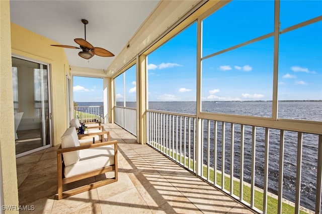 sunroom / solarium with ceiling fan and a water view