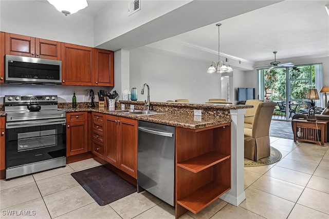 kitchen with stainless steel appliances, kitchen peninsula, ornamental molding, light tile patterned flooring, and dark stone countertops