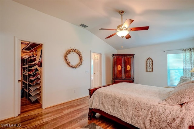 bedroom with a closet, a walk in closet, wood-type flooring, lofted ceiling, and ceiling fan