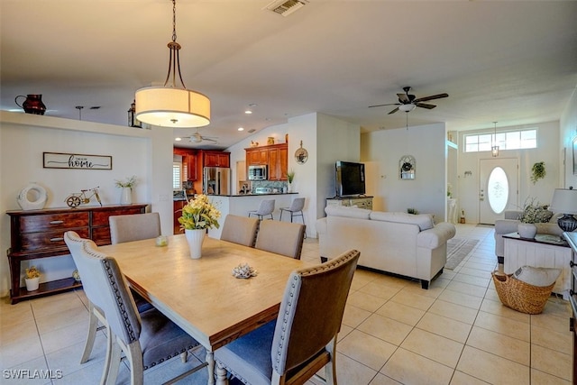 dining space featuring ceiling fan, light tile patterned floors, and vaulted ceiling