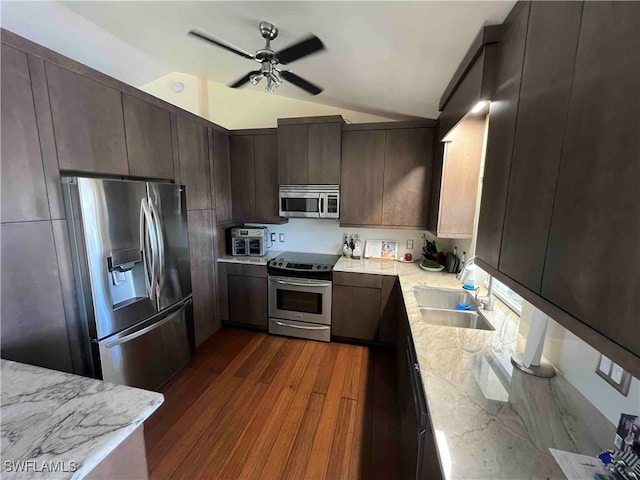 kitchen featuring stainless steel appliances, sink, light stone counters, dark hardwood / wood-style floors, and vaulted ceiling