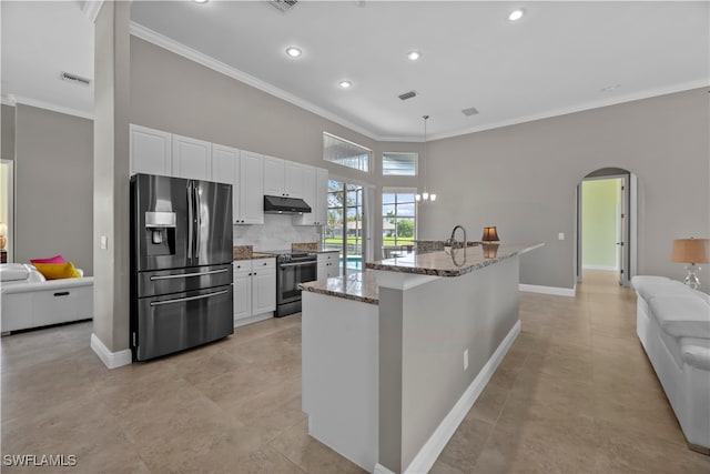 kitchen featuring stainless steel appliances, white cabinets, an island with sink, and light stone counters