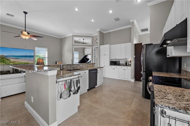 kitchen with sink, appliances with stainless steel finishes, dark stone counters, a spacious island, and white cabinets