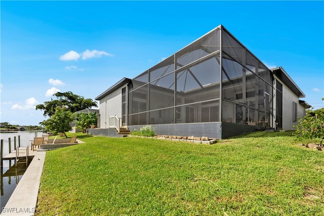 rear view of house with glass enclosure and a yard