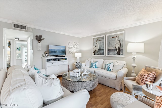 living room with hardwood / wood-style floors, ornamental molding, and a textured ceiling