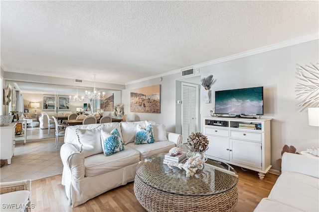 living room with a textured ceiling, light hardwood / wood-style floors, crown molding, and a notable chandelier