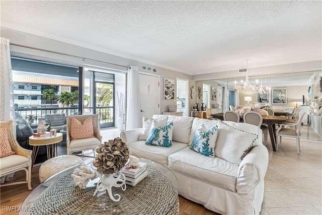 living room with a textured ceiling, ornamental molding, light tile patterned floors, and an inviting chandelier