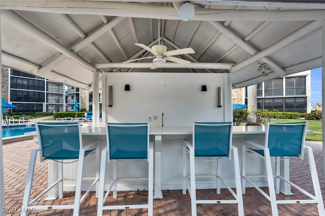 view of patio with ceiling fan and a bar