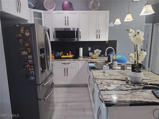 kitchen with pendant lighting, white cabinets, decorative backsplash, appliances with stainless steel finishes, and light stone counters