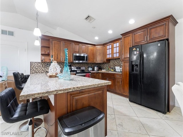 kitchen with kitchen peninsula, pendant lighting, stainless steel appliances, and vaulted ceiling