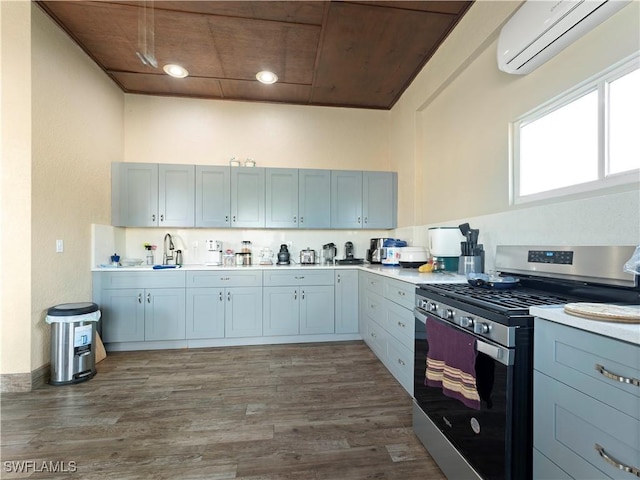 kitchen featuring a wall unit AC, gray cabinets, dark hardwood / wood-style floors, and stainless steel range with gas stovetop