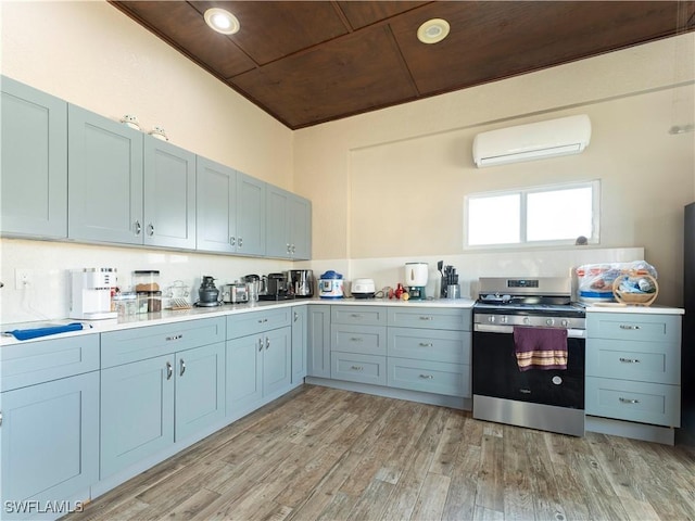 kitchen with an AC wall unit, stainless steel range, and light hardwood / wood-style flooring