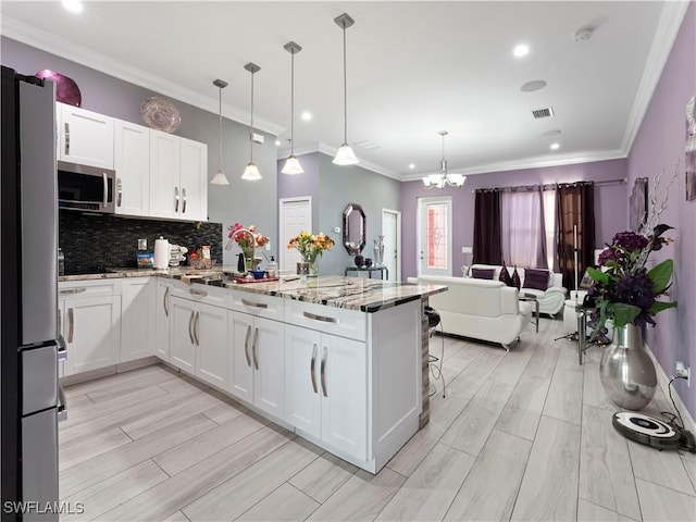 kitchen with appliances with stainless steel finishes, decorative light fixtures, white cabinetry, and light stone counters