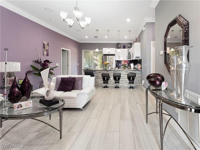 living room with light hardwood / wood-style floors, an inviting chandelier, and crown molding