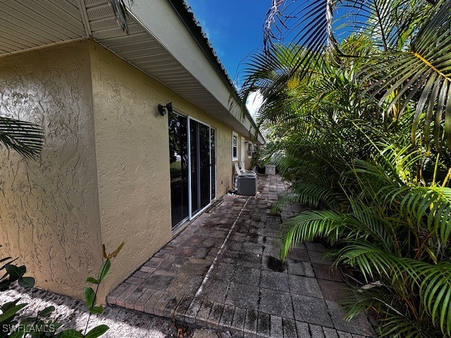 view of property exterior with central AC unit and a patio