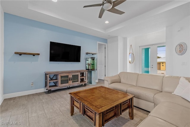 living room featuring ceiling fan and a tray ceiling