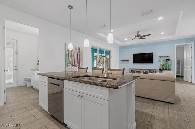 kitchen featuring sink, white cabinetry, decorative light fixtures, a tray ceiling, and dishwasher