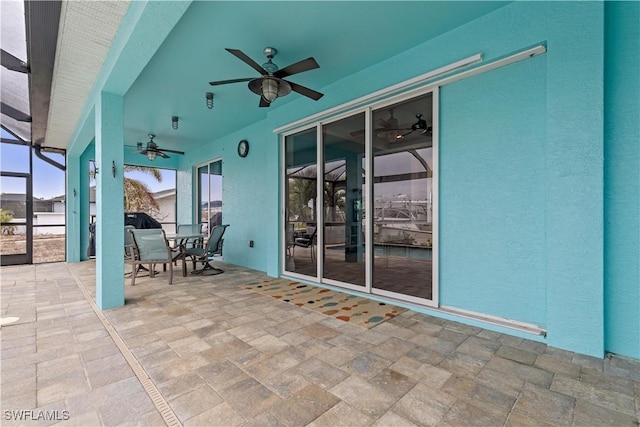 view of patio with ceiling fan and glass enclosure