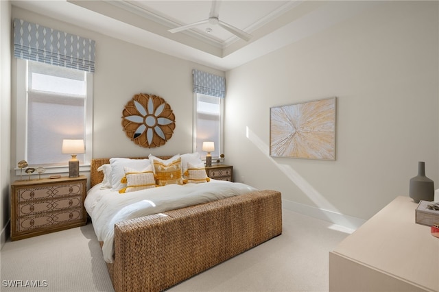 carpeted bedroom featuring a tray ceiling, ornamental molding, and ceiling fan