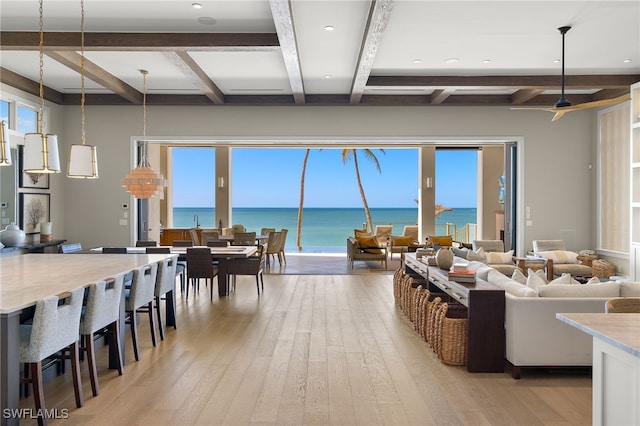 living room featuring light wood-type flooring, beamed ceiling, and a water view