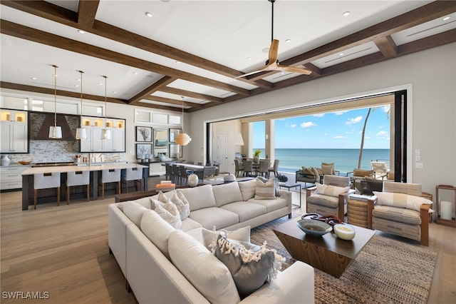 living room with a water view, beam ceiling, and light hardwood / wood-style flooring