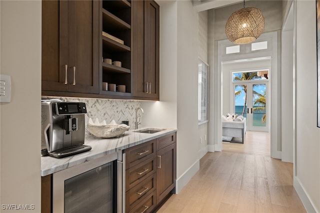 bar featuring pendant lighting, sink, dark brown cabinetry, and beverage cooler